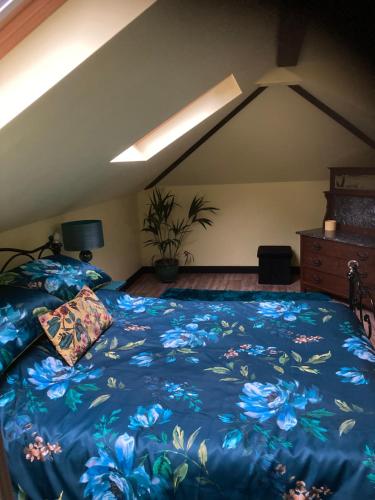 a bedroom with a bed with a blue floral bedspread at Woodland Retreat, Market Lane, Blundeston, Lowestoft in Blundeston