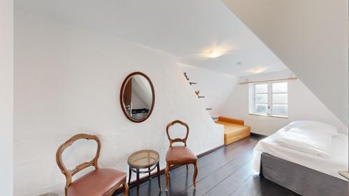 a bedroom with two chairs and a bed and a mirror at Strandhaus Landsitz Vierjahreszeiten in Klein Zicker