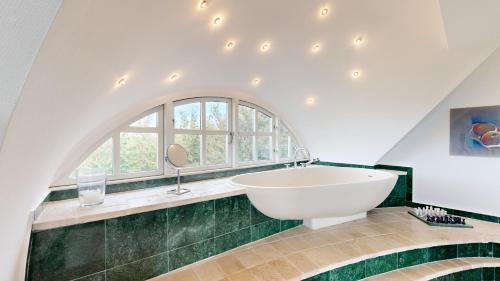 a bathroom with a large white tub and a window at Strandhaus Landsitz Vierjahreszeiten in Klein Zicker
