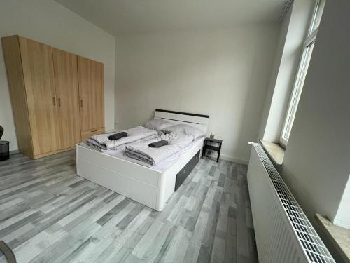 - une chambre avec un lit blanc et du parquet dans l'établissement Schöne einfache Ferienwohnung in Oldenburg, à Oldenbourg