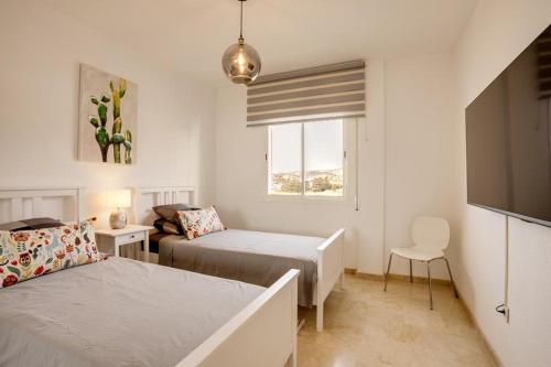 ein weißes Schlafzimmer mit 2 Betten und einem Fenster in der Unterkunft Apartamento Mirador - Marina Bay in Estepona