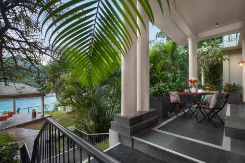 a porch with a table and a palm tree at Anand Kashi by the Ganges Rishikesh - IHCL Seleqtions in Rishīkesh