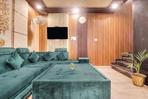 a living room with a green couch and a tv at Townhouse Hotel Rooftop in Rishīkesh