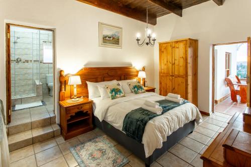 een slaapkamer met een groot bed en een badkamer bij Ravenscliff White House in Oudtshoorn