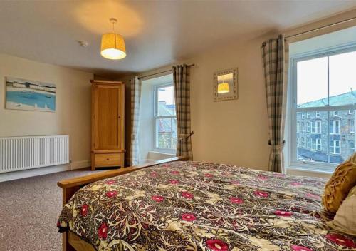 a bedroom with a large bed with a flowered blanket at Luxury 4 Bedroom Seaside Apartment - Glan Y Werydd House in Barmouth