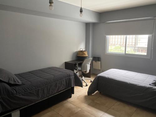 a bedroom with two beds and a desk and a window at Oasis 1.6 in Mendoza