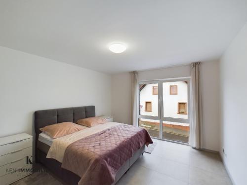 een slaapkamer met een bed en een groot raam bij Apartments by KEN in Ramstein-Miesenbach