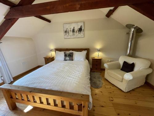um quarto com uma cama grande e uma cadeira em The Granary Stunning Barn Conversion em Broadwoodkelly