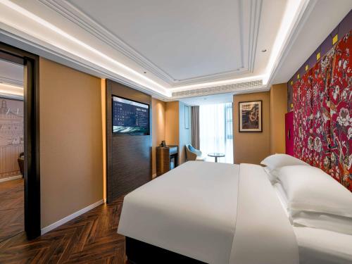 a bedroom with a large white bed in a room at Zhangjiajie Hero Boutique Hotel in Zhangjiajie