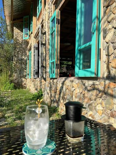 a glass vase sitting on a table in front of a building at Little House in KhauPha, Mu Cang Chai - homestay, cuisine, cafe in Mù Cang Chải