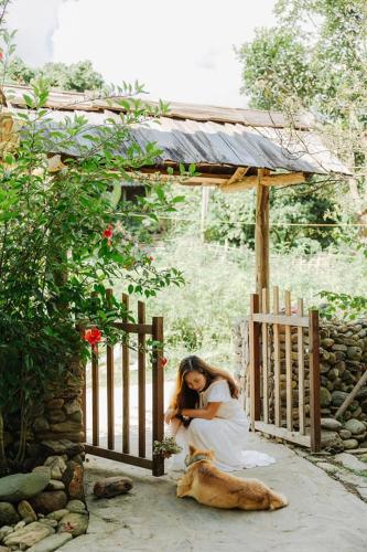 a woman sitting in a gate with a dog at Little House in KhauPha, Mu Cang Chai - homestay, cuisine, cafe in Mù Cang Chải