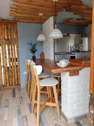 a kitchen with a counter with chairs and a table at Talita Cumi in Villa Santa Cruz del Lago