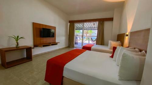 a hotel room with a large bed and a television at Sunsol Isla Caribe in Puerto Fermín
