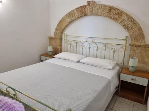 a bedroom with a white bed with an arch above it at Agriturismo Le Tagliate in Uggiano la Chiesa