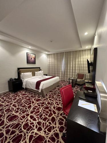 a hotel room with a bed and a red chair at Al Joud Hotel Makkah in Makkah