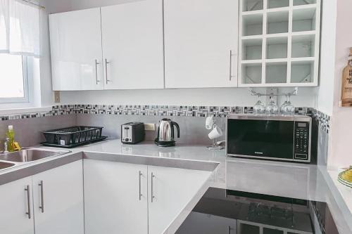 a white kitchen with white cabinets and a sink at Paradise Point Villa Negril in Orange Bay