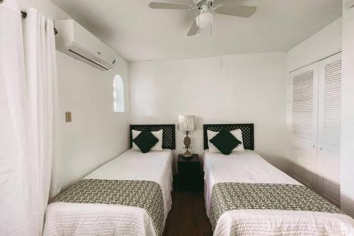 two beds in a room with white walls at Paradise Point Villa Negril in Orange Bay