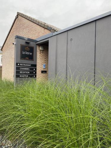 a sign in front of a building with tall grass at Les Thermes de Spa by La Cour de la Reine Hôtel, Suites & accès gratuit au centre thermal in Spa