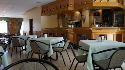 un restaurante con mesas y sillas y un bar en Hotel Larry en Cee