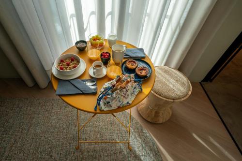 una mesa amarilla con comida y bebidas. en SUTRooms en Braga