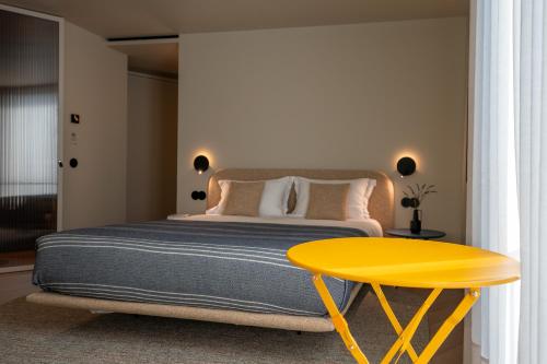a bedroom with a bed and a yellow table at SUTRooms in Braga
