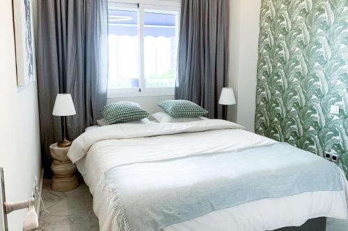 a bedroom with a bed with blue and white sheets at LUX Apt Puerto Banus-Pool-Terrace 5 min to beach in Marbella