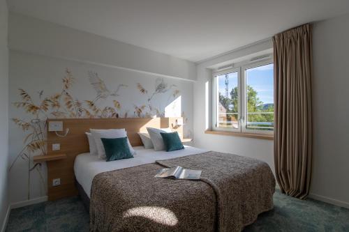 a bedroom with a large bed with a window at SHANA Hôtel & Résidence in Chanaz