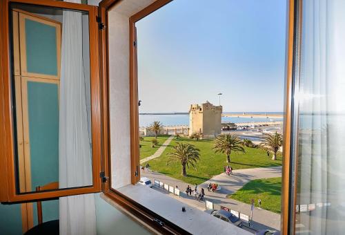 una finestra con vista su una spiaggia e su un castello di Hotel Elisa a Porto Torres