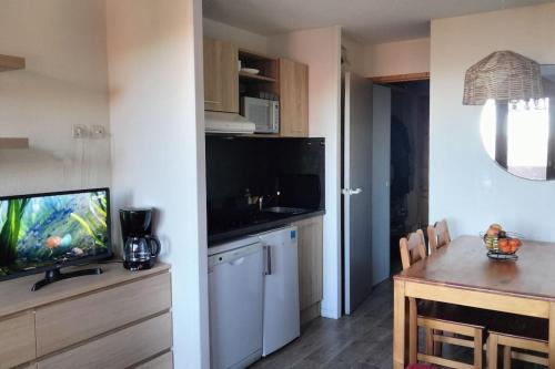 une cuisine avec une télévision et une table avec une salle à manger dans l'établissement Bel appartement vue montagne, à La Plagne Tarentaise