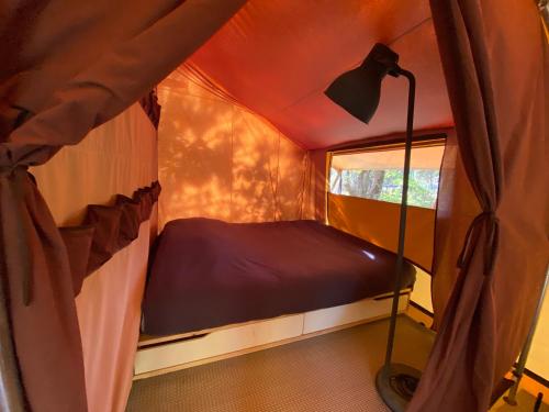 een kleine kamer met een bed in een tent bij Camping la Kahute, tente lodge au coeur de la forêt in Carcans
