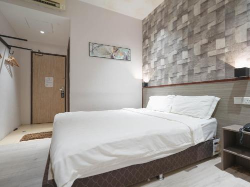 a bedroom with a large white bed and a wooden wall at Noble Hotel Express, Check in 10PM, Check out 9AM in Singapore