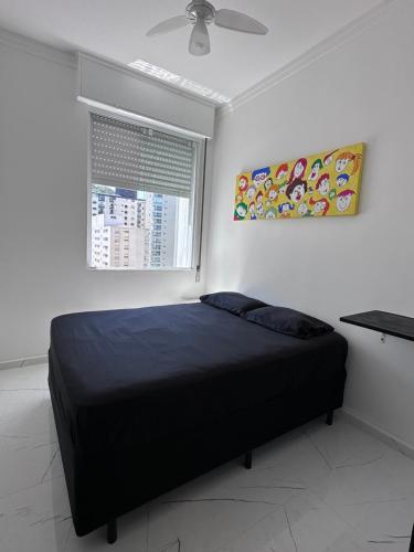 a bedroom with a black bed and a window at Frente ao mar Pitangueiras - 3 suítes in Guarujá