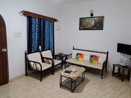 a living room with chairs and a table and a tv at Brittos Homestay in Mandrem