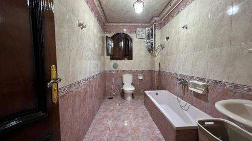 uma casa de banho com uma banheira, um WC e um lavatório. em Charming Apartment in 6th October Cairo Giza Family Only em Cidade 6 de Outubro