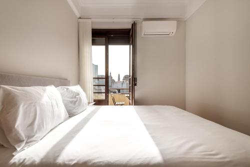 a bedroom with a bed with white sheets and a window at Rivoli Apartments in Porto