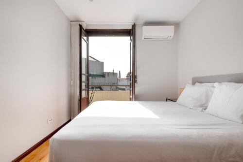 a white bed in a room with a window at Rivoli Apartments in Porto