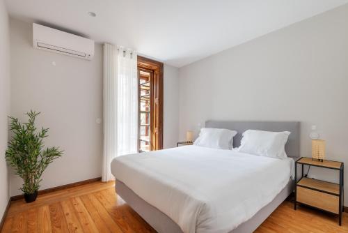 a white bedroom with a large bed and a window at Rivoli Apartments in Porto