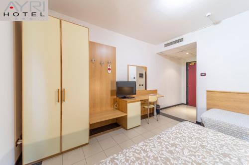 una camera con letto e scrivania con TV di Hotel Ayri a Medesano
