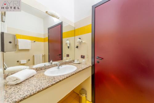 bagno con lavandino e porta rossa di Hotel Ayri a Medesano