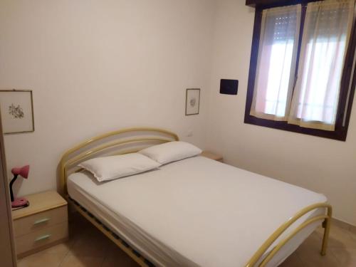 a white bed in a room with a window at Residence Corallo in Rosolina Mare