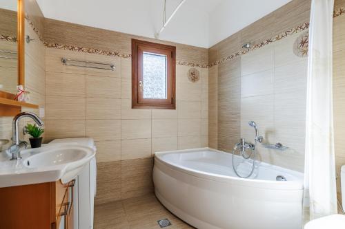 y baño con bañera y lavamanos. en Villa Christina near Stafylos beach, en Skopelos Town