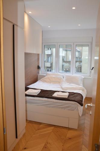 a bedroom with a bed and two windows at Unca in Belgrade