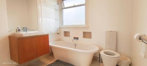 a bathroom with a tub and a toilet and a window at Park View Garden in London