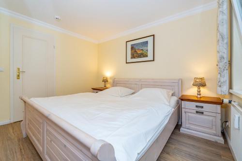a bedroom with a large white bed and two night stands at Westerhörn 46 15 in Keitum