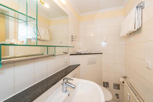 a white bathroom with a sink and a mirror at Westerhörn 46 15 in Keitum