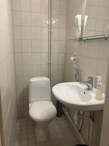 a white bathroom with a toilet and a sink at Bella Hostel in Turku
