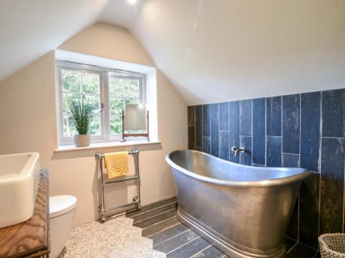 a bathroom with a tub and a toilet and a window at The Carriage House in Lyme Regis