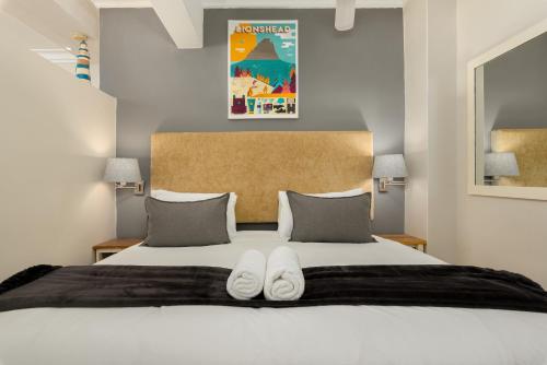 ein Schlafzimmer mit einem Bett mit zwei weißen Schuhen darauf in der Unterkunft Caprice Court 6 in Kapstadt