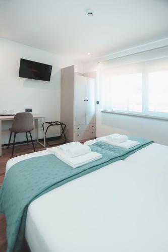 a white bedroom with a bed and a desk at Alma Candida 16 in Ganfei