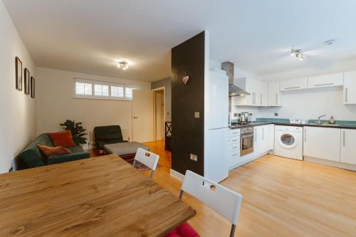 een keuken en een woonkamer met een houten tafel in een kamer bij Brick Lane & Shoreditch London Apartment in Londen
